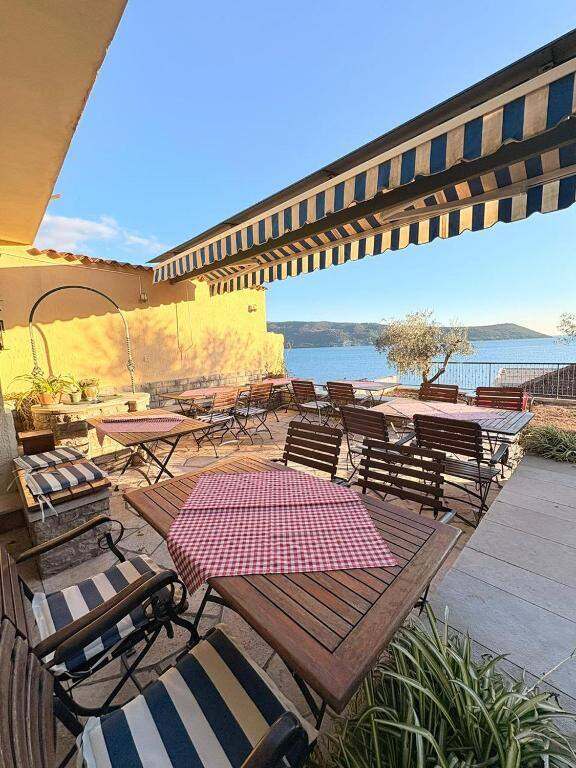 Shaded terrace with tables facing the sea at Garni Hotel Bokeška Noć