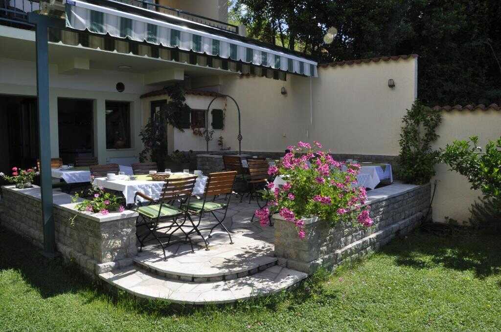 Breakfast patio with tables and flowers at Garni Hotel Bokeška Noć
